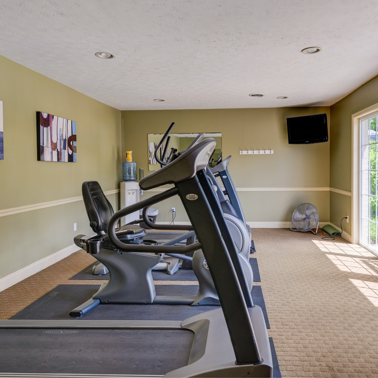 Fitness area with treadmill and bike facing view of outside